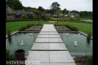 Strakke vijver met fonteintjes en looppad van stapstenen naar pergola