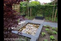 Strakke heldere vijver met decoratie van rotsblokken op bodem