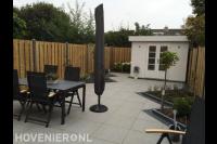 Tuin met tuinhuis, hout beton schutting en bestrating van witte tegels
