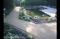 Tuinpad van gebakken klinkers langs vijver