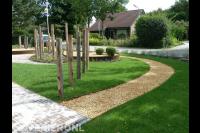 Voortuin met gazon, grindpad, border van cortenstaal en houten palen