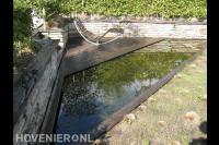 Heldere vijver met vlonder en ligstoel