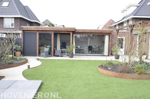 Stadstuin met kunstgras en eettafel onder een boom