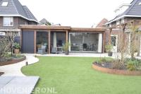 Stadstuin met kunstgras en eettafel onder een boom