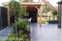 Tuinaanleg met sierbestrating, plantenbak en houten overkapping