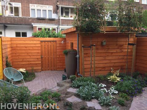 Achtertuin met schutting, tuinhuis, bestrating en nieuwe beplanting