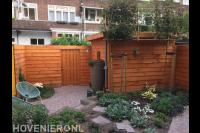 Achtertuin met schutting, tuinhuis, bestrating en nieuwe beplanting