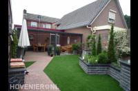 Achtertuin met terrasoverkapping, kunstgras en plantenbakken 1