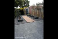 Achtertuin met bestrating, kiezels en plantenbakken