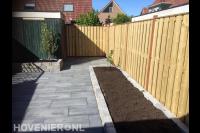 Achtertuin met houten schutting en bestrating van natuursteen