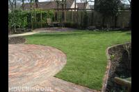 Achtertuin met gazon en bestrating in cirkelpatroon