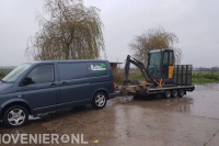 Minigraver op aanhanger achter bedrijfsbus