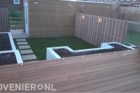 Achtertuin met houten vlonder, kunstgras en plantenbakken 1