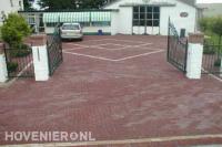 Sierhekwerk en poort bij oprit van rode stenen