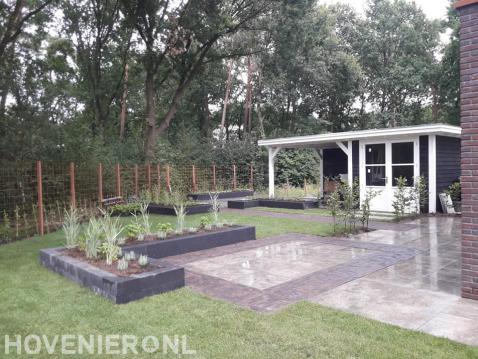 Tuinaanleg met veranda, sierbestrating, gazon en plantenbakken
