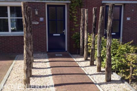 Onderhoudsarme voortuin met houten palen als decoratie