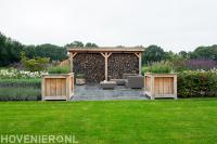 Terras van natuursteen en houten overkapping met haardhout