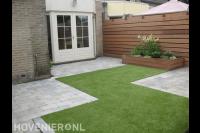 Achtertuin met houten schutting, kunstgras en straatwerk van klinkers