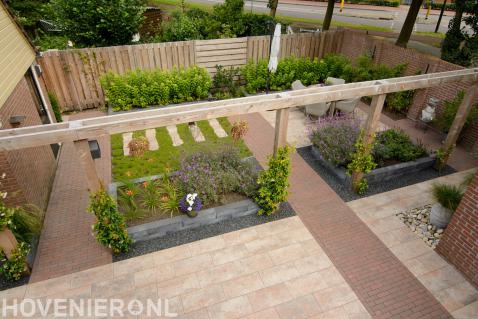 Strakke tuin met verhoogde borders en grote houten pergola