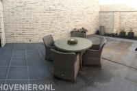 Strak terras van grote antraciet tegels met tuinset