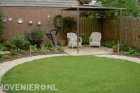 Zithoek met overkapping bij rond gazon