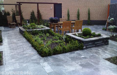 Strakke tuin met pergola en bestrating van natuursteen