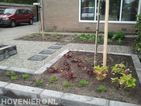 Kleine voortuin met plantenbakken en grind