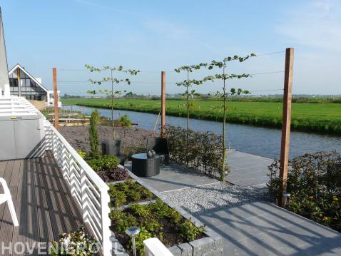 Moderne tuin aan het water met bestrating, pergola en leibomen 2