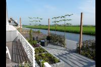 Moderne tuin aan het water met bestrating, pergola en leibomen 2