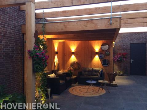 Houten overkapping met loungeset en tuinverlichting