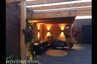 Houten overkapping met loungeset en tuinverlichting