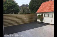 Tuinaanleg met keramische tegels en houten schutting