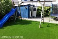 Achtertuin met speeltuin met kunstgras