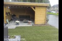 Tuin aan het water met houten overkapping en gazon van graszoden