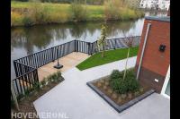 Tuin aan het water met bestrating, borders, gazon en vlonder