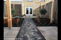 Achtertuin met bestrating, pergola's en cortenstaal plantenbakken