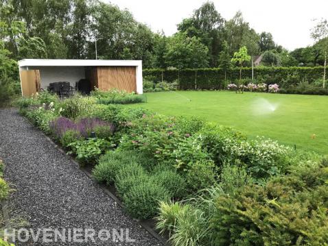 Groene tuin met groot gazon en luxe overkapping
