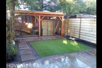 Achtertuin met sierbestrating, kunstgras en luxe veranda