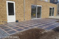 Terras van grote siertegels en gebakken klinkers