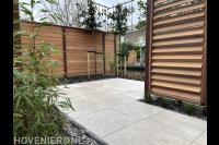 Tuin aan het water met houten schermen en leibomen