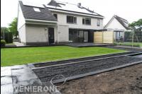 Strakke achtertuin met gazon en donkere bestrating