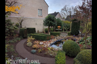 Tuin met vijver en vaste planten en haagplanten in borders