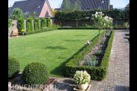 Ruime tuin met groot gazon, hagen en leibomen