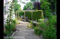 Grindpad naar zithoek met vlonder en pergola bij vijver