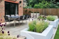 Terras van betontegels en witte bloembakken met siergras en buxus