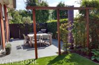 Tuin met kunstgras, pergola en terras van grote natuurstenen tegels