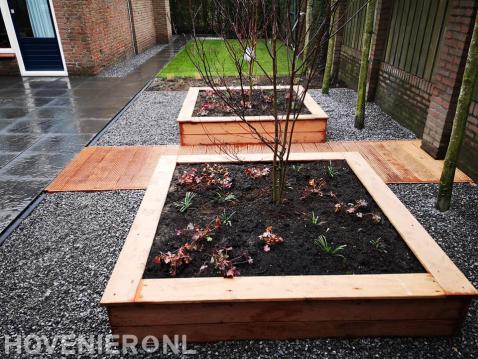 Tuin met houten vlonder en plantenbakken van hout