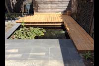 Bestrating en houten vlonder bij kleine vijver