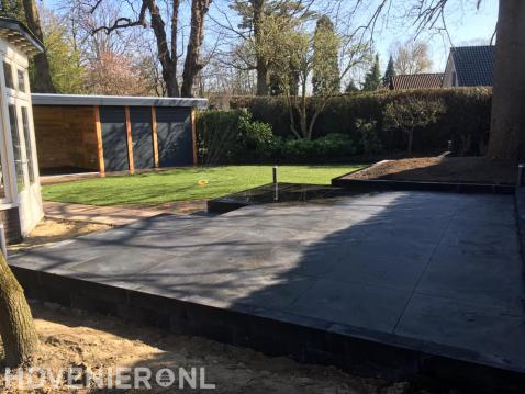 Tuin met verhoogd terras, gazon en overkapping