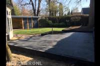 Tuin met verhoogd terras, gazon en overkapping